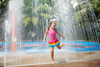 As crianças do círculo do arco-íris do parque do pulverizador de água molham o parque colorido do respingo da água do campo de jogos
